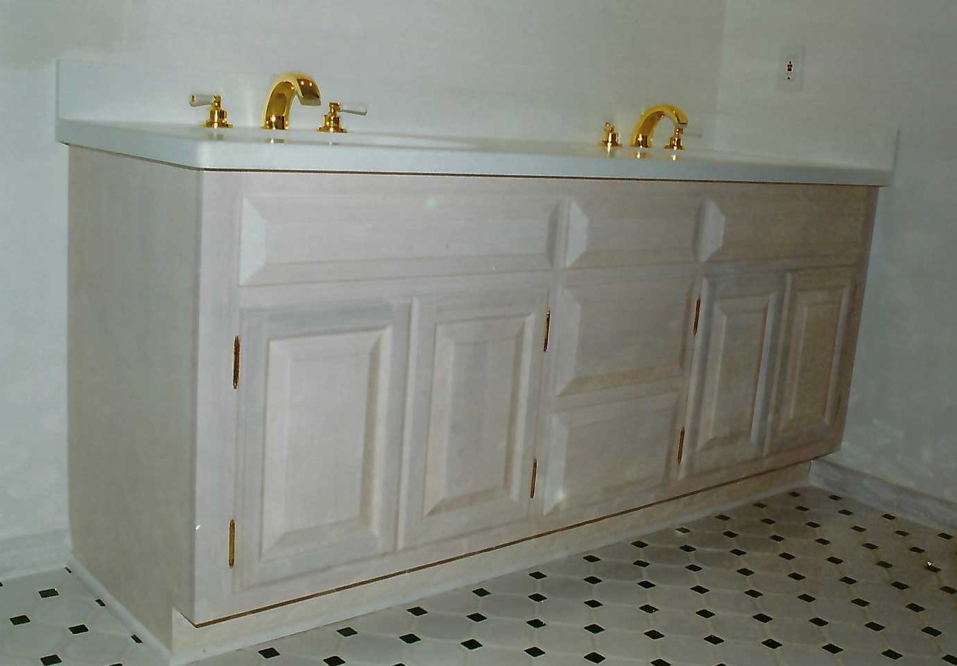 a white bathroom countertop with golden faucets