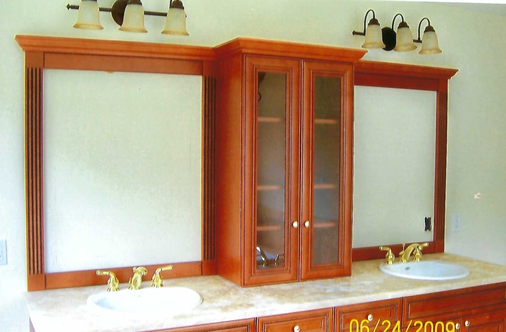 a bathroom countertop with a cabinet between two sinks