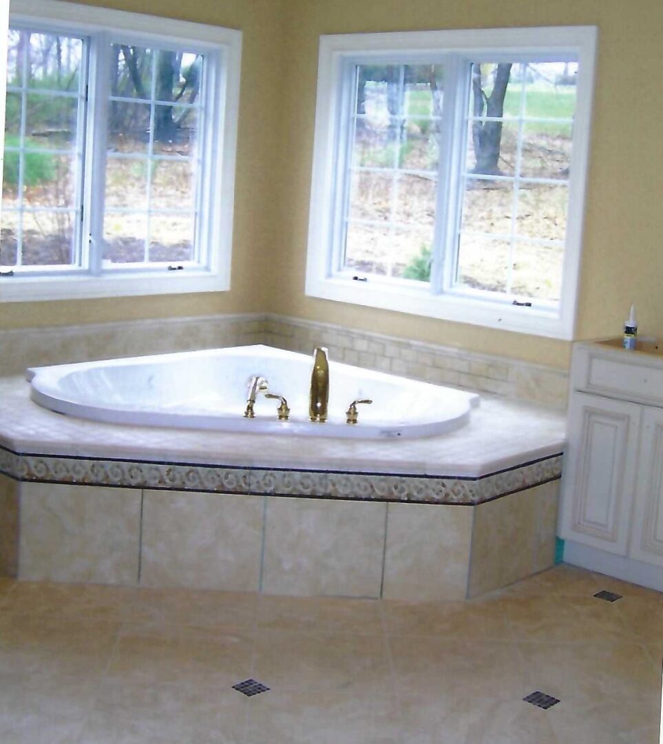 a tub deck in a corner of a bathroom near two windows