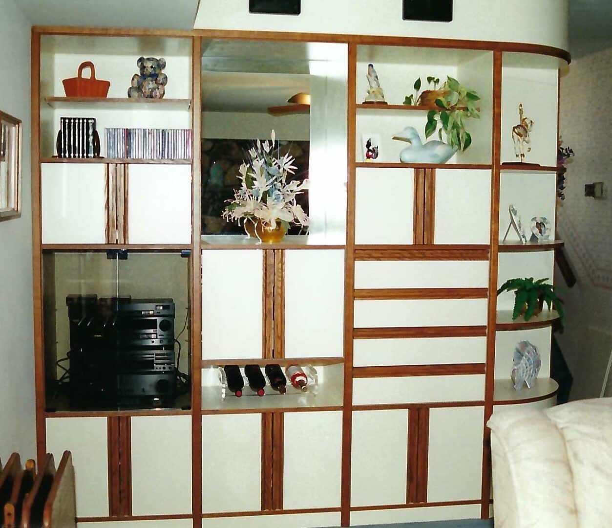 a built-in cabinet with flower vases, bottles of wine, and a radio